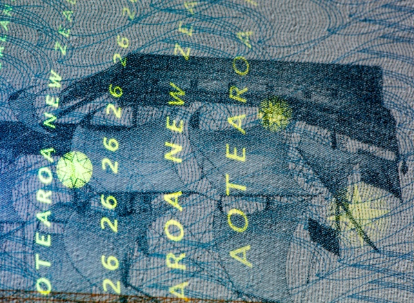 Gros plan d’une page d’un passeport néozélandais montrant un navire ancien et du texte en filigrane, éclairés à l’infrarouge
