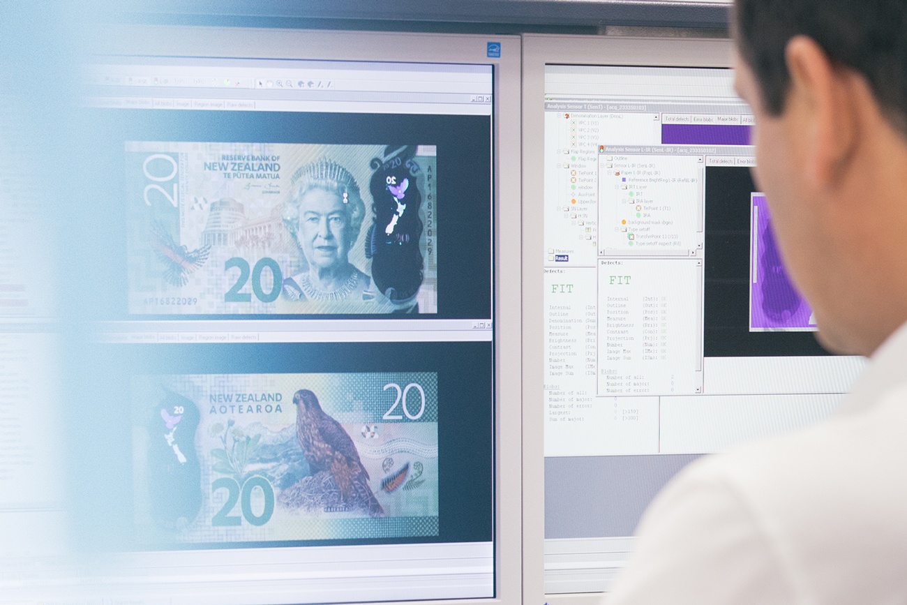 Man looks at computer screen showing 20 New Zealand dollar bill